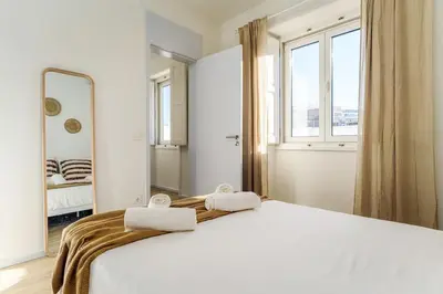 a bedroom with a white bed and a mirror at Modern & Bright - Faro Mercado Apt 22 by Lisbeyond in Faro