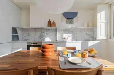 a kitchen with a wooden table with chairs and a dining room at Modern & Bright - Faro Mercado Apt 22 by Lisbeyond in Faro