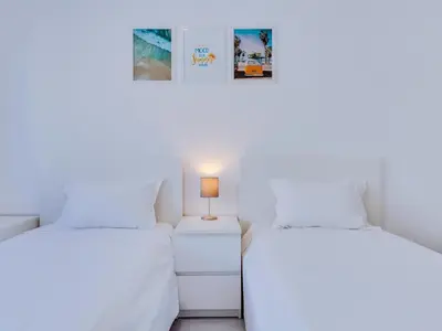 two beds in a room with white walls at AL - Apartamento Quarteira Avenida in Quarteira