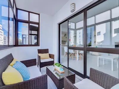 a living room with a couch and chairs and windows at AL - Apartamento Quarteira Avenida in Quarteira