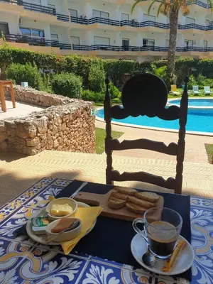 a table with a tray of food and a cat laying on a building at Apartamentos Mar-Bel Sol in Vilamoura