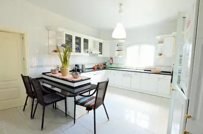 a kitchen with white cabinets and a table and chairs at Suites & Beds DP Albufeira in Albufeira