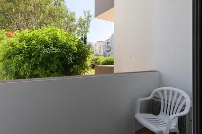 a white chair sitting on a balcony with a window at Roberto Quarteira Central in Quarteira