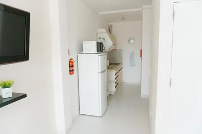 a white kitchen with a refrigerator and a tv at Happy House in Quarteira