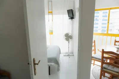 a room with a bed and a table and a window at Happy House in Quarteira