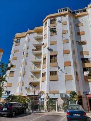 a tall building with cars parked in front of it at Happy House in Quarteira