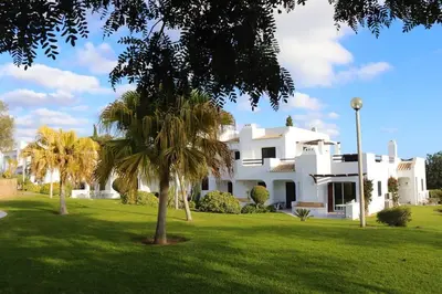 a large white house with palm trees in the yard at Excellent 1 Bedroom Villa - em Clube Albufeira Garden Village in Albufeira
