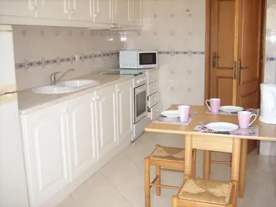 a kitchen with white cabinets and a table and a microwave at Apartamentos Monica in Quarteira