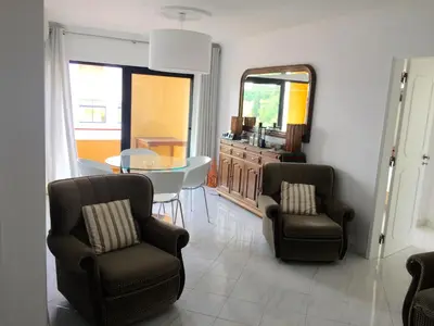 a living room with two chairs and a table and a mirror at Quarteira Paul Harris Apartment in Quarteira