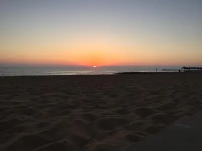 a sunset on a beach with the ocean at Quarteira Paul Harris Apartment in Quarteira