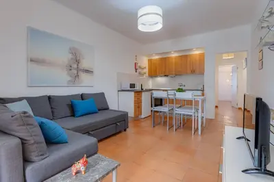 a living room with a couch and a kitchen at VILA MAGNA - Apart renovado para 4 com piscina e Ar condicionado in Albufeira