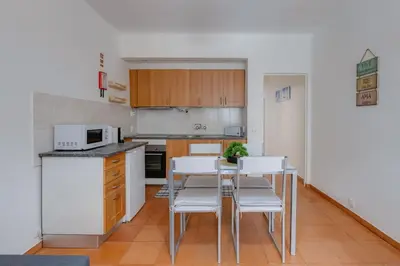 a kitchen with a table and some white chairs at VILA MAGNA - Apart renovado para 4 com piscina e Ar condicionado in Albufeira