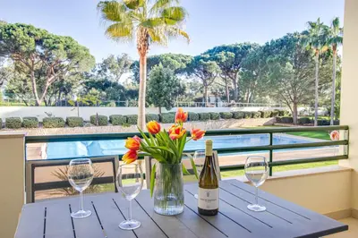 a table with wine glasses and a vase of flowers at Lovely 2BD Apart 500m Beach AC Wi-Fi Pool Balcony in Albufeira