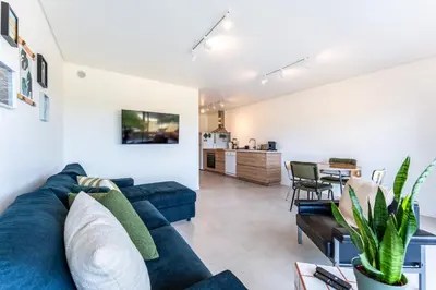 a living room with a blue couch and a kitchen at Tasteful 1 BDR Flat W/Balcony & Pool by LovelyStay in Quarteira