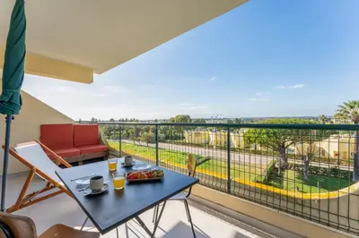 a balcony with a table and chairs and a view at Tasteful 1 BDR Flat W/Balcony & Pool by LovelyStay in Quarteira