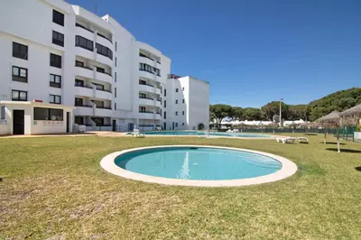 a swimming pool in the grass in front of a building at Tenis Golfmar in Vilamoura