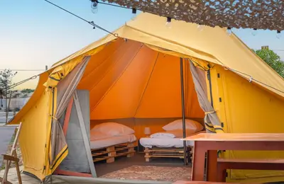 a yellow and orange tent with two beds in it at Glamping Camp Faro in Faro