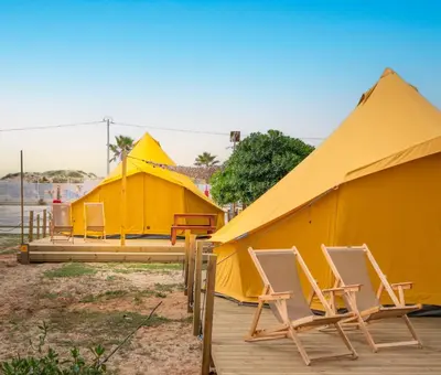 a row of yellow tents with chairs in front of them at Glamping Camp Faro in Faro