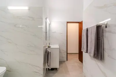 a bathroom with white marble walls and a toilet at Vila Amélia by Sunnyway in Albufeira