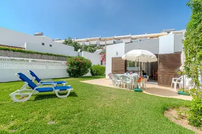 a yard with chairs and a table and an umbrella at Vila Amélia by Sunnyway in Albufeira