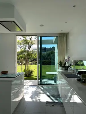 a kitchen with white counters and a large window at Casa Papoila in Albufeira