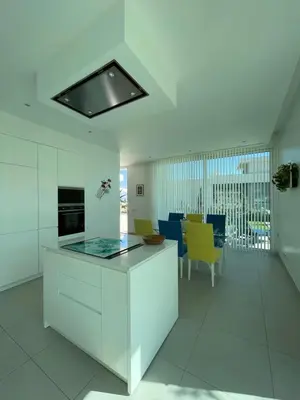 a kitchen with white cabinets and yellow chairs at Casa Papoila in Albufeira