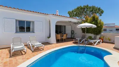 a patio with a table and chairs and a swimming pool at Villa Rosa in Vale do Lobo