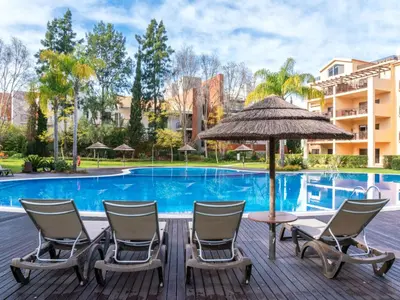 a deck with chairs and an umbrella next to a pool at Apartment Triplex Vilamoura VIP Properties by Interhome in Vilamoura