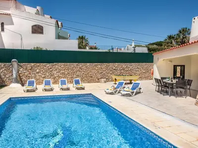a swimming pool with chairs and a table and a house at Villa Corcovada V4 VIP Properties by Interhome in Albufeira