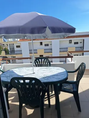 a table and chairs with an umbrella on a balcony at AREIAS SOL in Albufeira