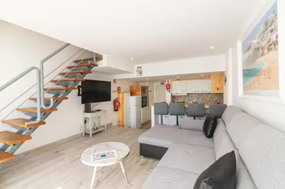 a living room with a couch and a spiral staircase at Flat with Pool T2 Duplex Montechoro in Albufeira