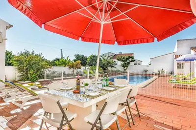 a patio with a table with a red umbrella at Villa Bento Dios in Galé