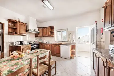 a kitchen with wooden cabinets and a table with fruits on it at Villa Bento Dios in Galé