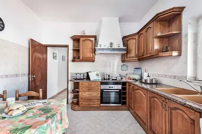 a kitchen with wooden cabinets and a sink at Villa Bento Dios in Galé