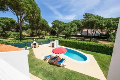 an overhead view of a swimming pool with a red umbrella at Villa Mendes in Vilamoura
