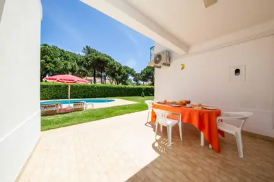 a dining room with a table and chairs and a pool at Villa Mendes in Vilamoura