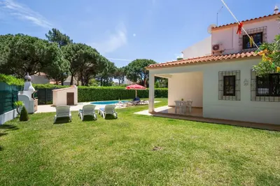 a house with a yard with chairs and a pool at Villa Mendes in Vilamoura