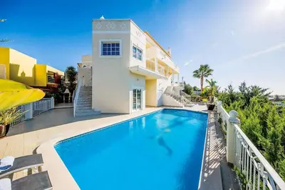a swimming pool in front of a house at Villa Encosta do Sol in Albufeira