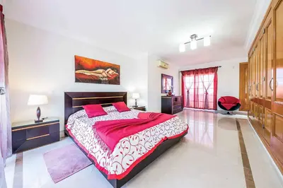 a large bedroom with a large bed with red sheets at Villa Encosta do Sol in Albufeira