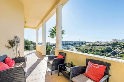 a balcony with chairs and a table with red pillows at Villa Encosta do Sol in Albufeira