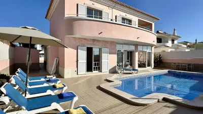 a villa with a swimming pool with chairs and an umbrella at Antonieta by Check-in Portugal in Albufeira