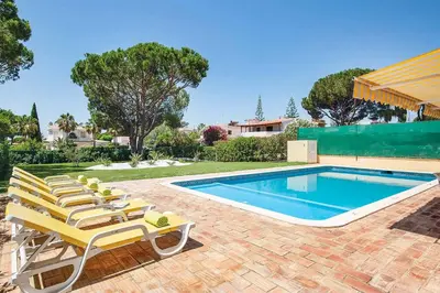 a swimming pool with lounge chairs next to a swimming pool at Villa Daffodil Golf in Vilamoura
