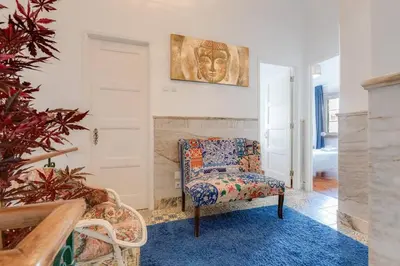 a living room with a chair and a painting on the wall at Casa LOTUS - Requinte e bom gosto para 6 pessoas no coração de Faro in Faro