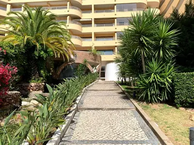 a walkway in front of a building with palm trees at Discovery Apartment Vilamoura in Vilamoura