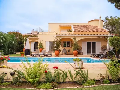 a villa with a swimming pool in front of a house at Beach villa Casa de Amanhã 450 mts to the beach with beautiful garden and heated saltwater pool in Albufeira