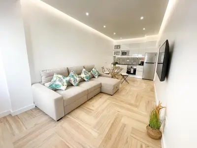 a living room with a white couch and a kitchen at Apartments Home Sweet Home in Faro
