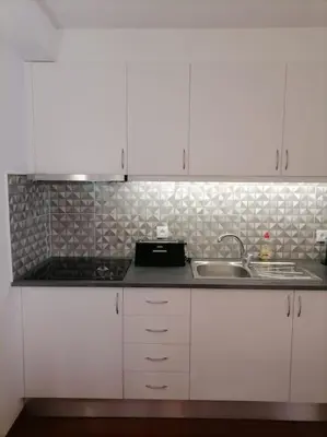 a kitchen with white cabinets and a sink at Cadete house in Albufeira