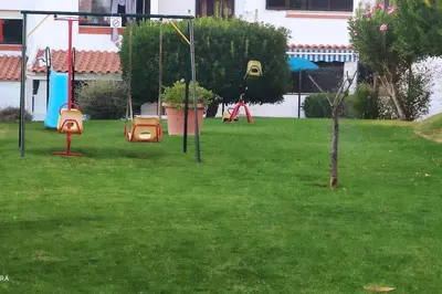 a playground with two swings in a yard at Cadete house in Albufeira