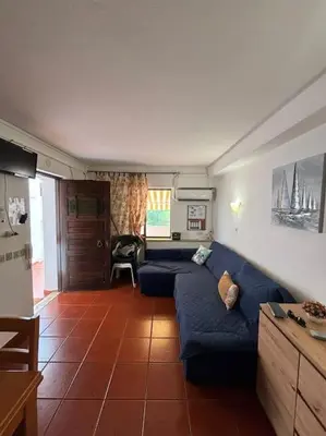 a living room with a blue couch and a kitchen at Cadete house in Albufeira