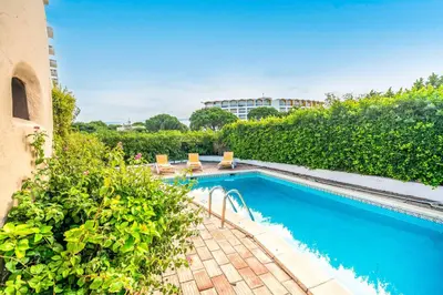 a swimming pool with chairs and plants next to a building at Villa Silveira in Vilamoura
